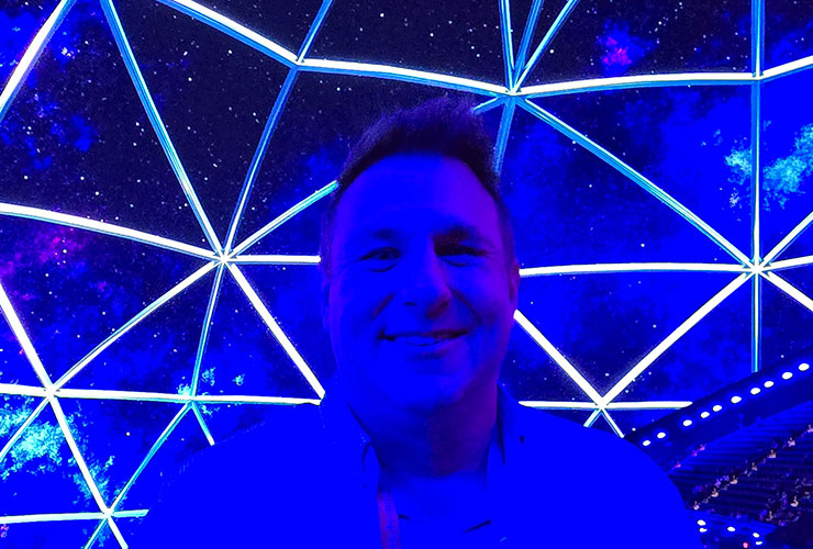 Doug Ryner, a well-known figure in the tech industry, standing in front of the Sphere at Las Vegas. He is wearing a dark suit and tie, and smiling at the camera.